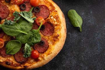 Freshly baked homemade pizza on a black background. View from above.