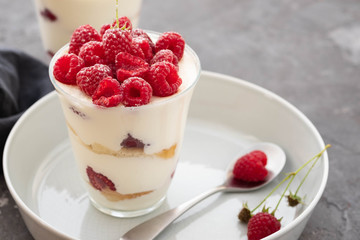 Tiramisu with raspberry in glasses on grey background. Italian dessert. Copy space.