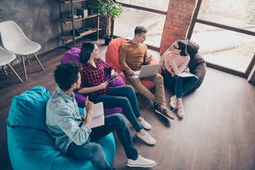 Fototapeta premium Above high angle view of cheerful stylish guys on bag chair managers preparing marketing data research report study education interns at industrial wooden loft interior workplace workstation