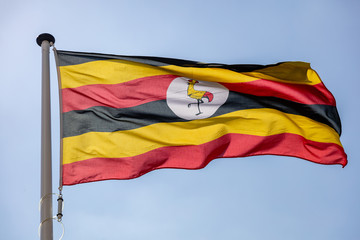 Uganda flag waving against clear blue sky