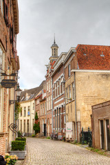 Idyllic street with historic houses and cobblestone pavement, in the background a churchtower; the charming Dutch city of Zutphen