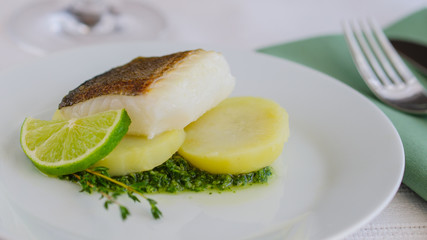 Baked fillet fish  with garnish and  sauce in the restaurant table .