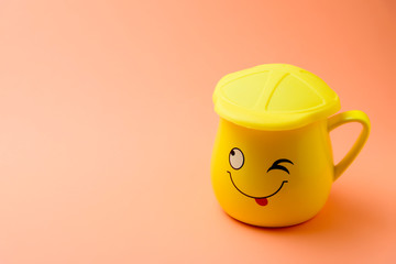 Yellow cup with a winking smile on a colored background