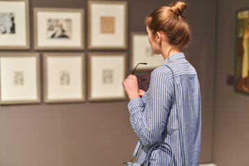 woman visitor in historical museum looking at pictures - obrazy, fototapety, plakaty