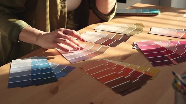 Young woman designer chooses from color palette and fabric samples the best for her client