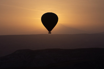 Hot air balloons flying over spectacular Cappadocia on sunset.