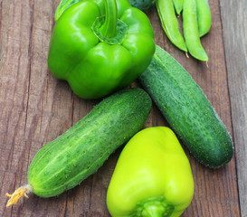 Group Ripe Green pepper and cucumber lying on a wooden background. Close up view from top.