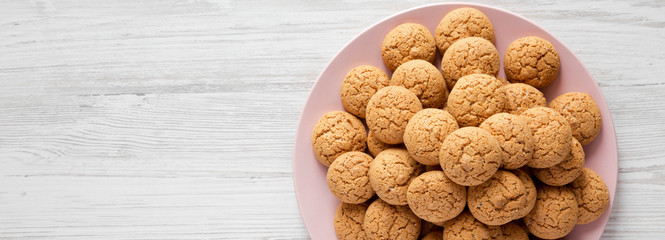 Almond cookies on a pink plate over white wooden background, top view. Flat lay, overhead, from above. Space for text.
