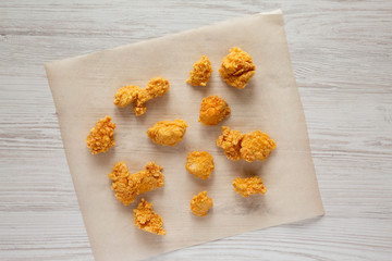 Chicken bites on a baking sheet on a white wooden background, top view. Flat lay, overhead, from above.