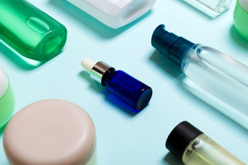 Top view of cosmetic products in different jars and bottles on blue background. Close-up of containers with copy space