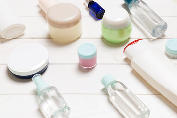 Close-up view of cosmetic bottles, jars, containers and sprays on white wooden background. Beauty concept with copy space
