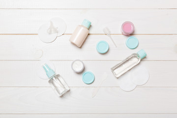 Top view of means for face care: bottles and jars of tonic, micellar cleansing water, cream, cotton pads on wooden background. Bodycare concept with empty cpace for your ideas