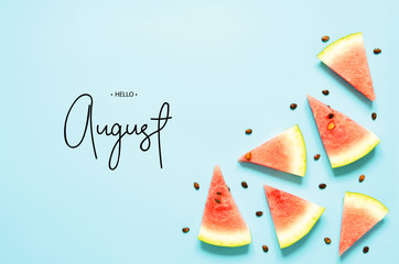 Inscription Hello August. Fresh red watermelon slice Isolated light blue background. Top view, Flat...