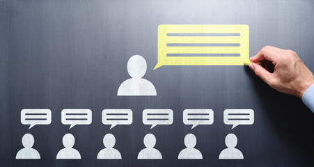 Business communication concept. Businessman drawing speech balloons on chalkboard.