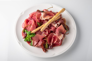 Slicing gourmet meat, prosciutto from beef and pork with berries, cheese, vegetables. Banquet festive dishes. Gourmet restaurant menu. White background.