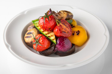 Appetizer of grilled vegetables from zucchini, eggplants, tomatoes, sweet peppers, onions. Rolls stuffed with cheese. Banquet festive dishes. Gourmet restaurant menu. White background.