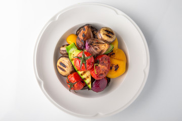 Appetizer of grilled vegetables from zucchini, eggplants, tomatoes, sweet peppers, onions. Rolls stuffed with cheese. Banquet festive dishes. Gourmet restaurant menu. White background.