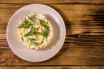 Salad with crab sticks, boiled eggs and cucumbers on a ceramic plate. Top view