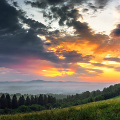 Fototapeta premium Sunset mountain landscape with hills and forest in background.