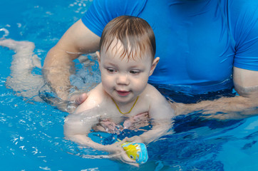 Fototapeta na wymiar little boy learns to swim in the pool with an instructor
