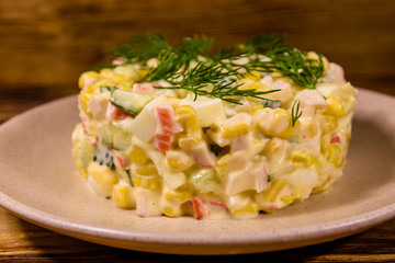 Salad with crab sticks, boiled eggs and cucumbers on a ceramic plate