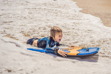 Happy Young boy having fun at the beach on vacation, with Boogie board