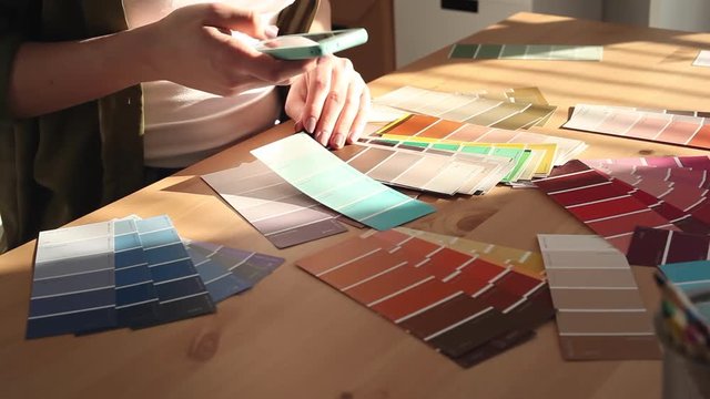 Young woman designer chooses from color palette and fabric samples the best for her client