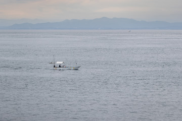 Obraz premium single boat at sea or ocean with mountain background.