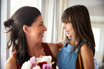 Smiling young white girl giving her mother a bunch of flowers on Motherâ€™s Day, close up