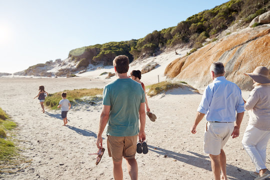 Back view of three generation white family exploring together on a sunny beach - Powered by Adobe