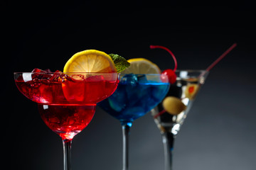 Two colorful cocktails and dry martini with green olives.