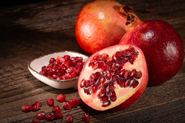 Granatäpfel und -Kerne mit Minze, Rosmarin und Deko auf brauner Holzfläche in gemütlicher Lichtstimmung.