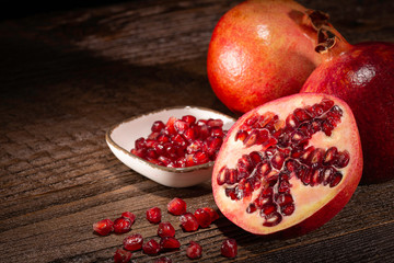 Granatäpfel und -Kerne mit Minze, Rosmarin und Deko auf brauner Holzfläche in gemütlicher Lichtstimmung.
