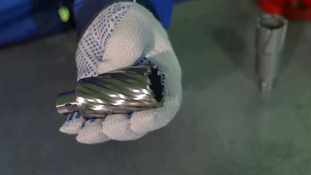 A man in gloves holds HSS crown bit in his hands
