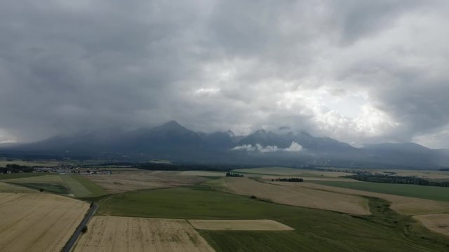 Fields In Front Of Mountains Covered In Clouds Flyover, High Tatras, Slovakia