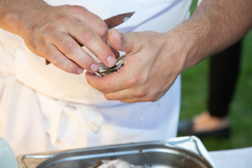 Obraz na płótnie Canvas man shucking fresh oysters with a knife