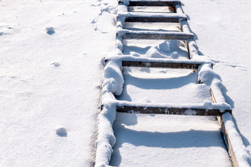 old wooden ladder lying in the snow shadow