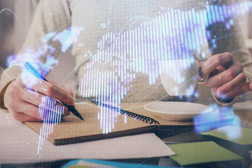 International business hologram over woman's hands taking notes background. Concept of success. Double exposure