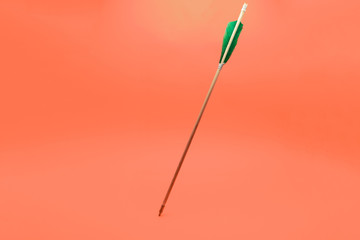 Old green wooden arrow on a beautiful peach background.