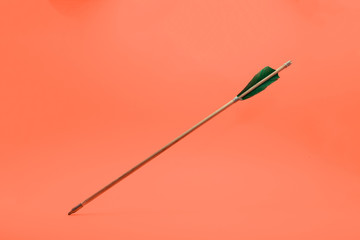 Old green wooden arrow on a beautiful peach background.