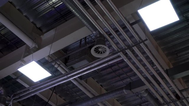 low angle of metal pipes of hvac system and lamps mounted to ceiling of big mall