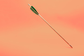 Old green wooden arrow on a beautiful peach background.