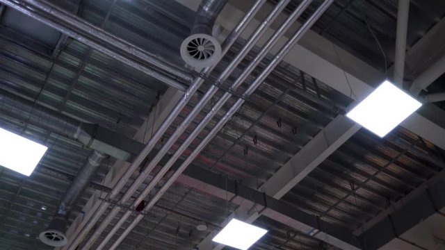 industrial hvac system pipes and lamps on ceiling of big shopping center