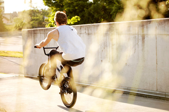 Bmx manual at concrete wall at sunset