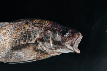 Fresh organic fish on ice on the market on dark vintage background  close-up.