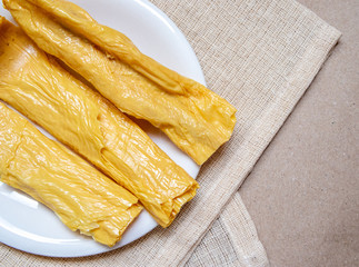 Dried yuba sticks or Fuzhu or dried bean curd In a white dish on a light brown cloth