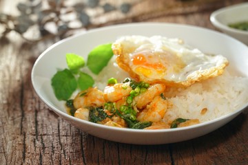 Thai food : Kaphrao Kung is Stirred and fried shrimps with holy basil and chilies served on steamed rice and fried egg. Shooting in studio for advertising. Thai and Asian food concept.