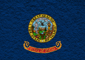 The national flag of the US state Idaho in against a gray wall with stony surface on the day of independence in color of blue red and yellow. Political and religious disputes, customs and delivery