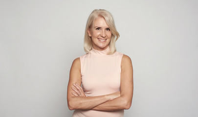 Beautiful 50 years lady with hands folded is smiling. Isolated