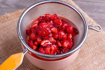 Slices of strawberries with sugar on a sieve
